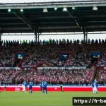 벨라루스 축구 리그 소개 - **"Authentic Belarusian Football Atmosphere"**: A wide shot inside a modest but vibrant Belarusian f...